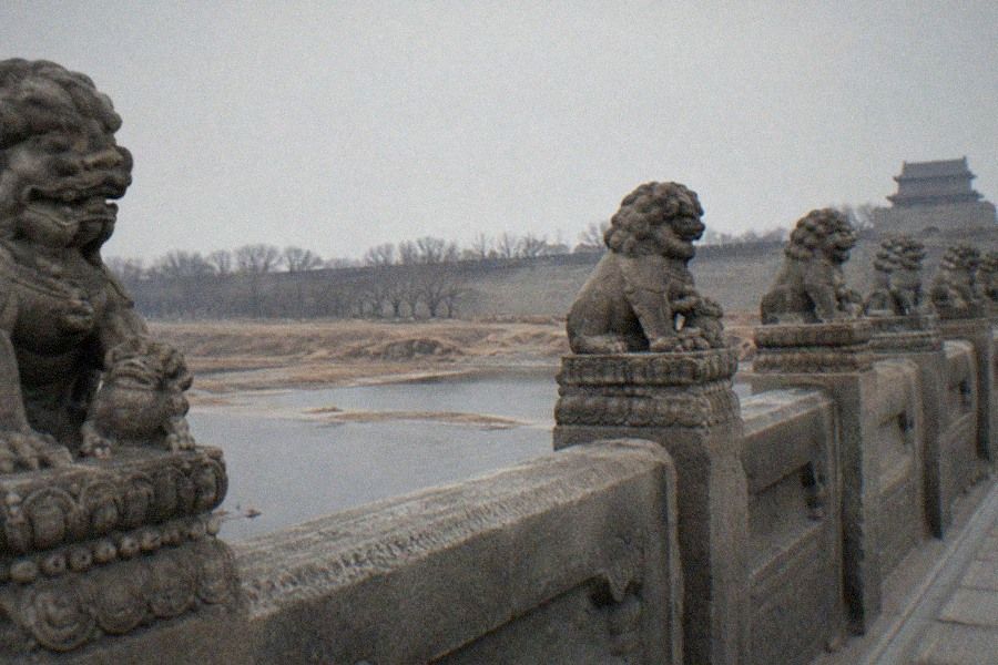 The stone Marco Polo Bridge beside Wanping Fortress in Fengtai, Beijing, with carved lions along the balustrade and the fortress walls beyond