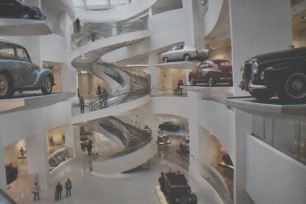 Vintage and modern cars displayed across the open floors of a large museum hall