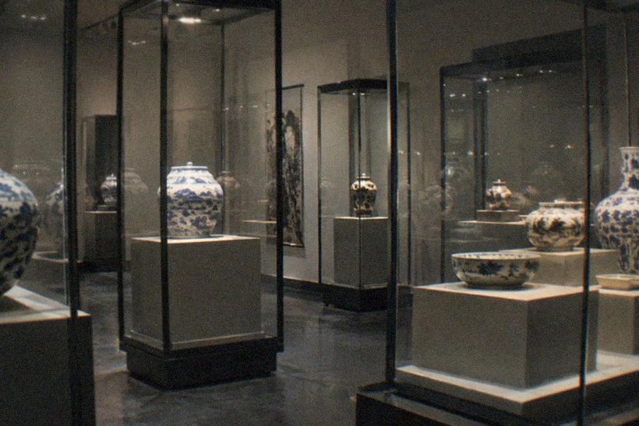 Spacious museum gallery with display cases of ancient Chinese artifacts along the walls