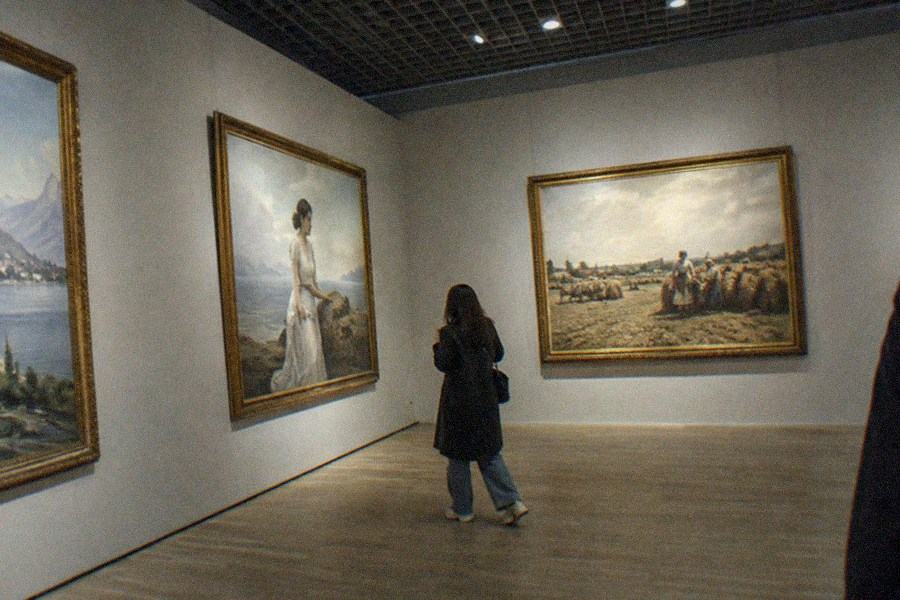 Visitors viewing large traditional Chinese ink paintings displayed in a bright museum gallery