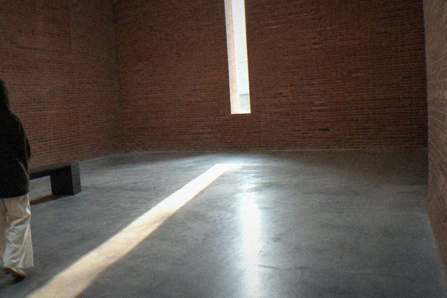 A sunken circular courtyard framed by red brick walls with reflected light on still water