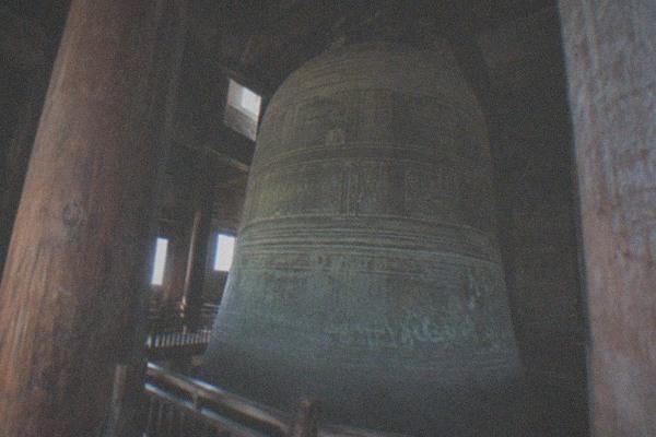 An ancient bronze bell displayed in a timber hall at the Great Bell Temple in Beijing