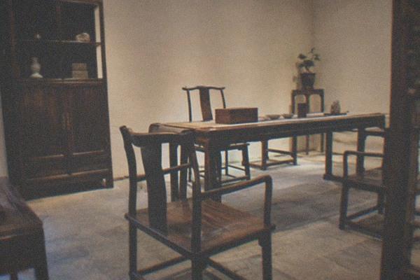 A quiet gallery interior with classical Chinese furniture displayed under warm lighting