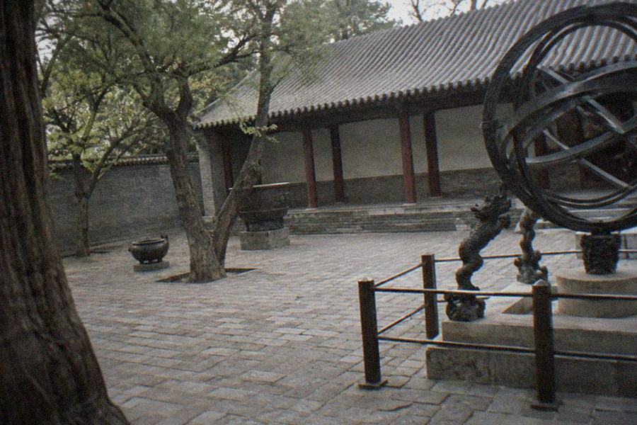 Close view of a large bronze armillary sphere instrument mounted on a stone pedestal on an old observatory rooftop