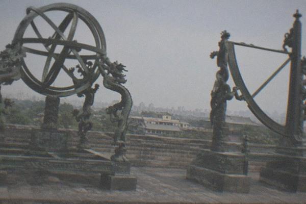 An old stone observatory platform in Beijing with bronze astronomical instruments mounted along its rooftop terrace under a clear sky