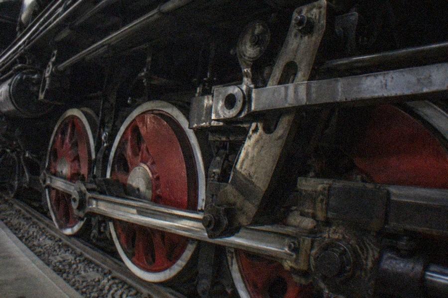 A black steam locomotive displayed on tracks inside a bright exhibition hall