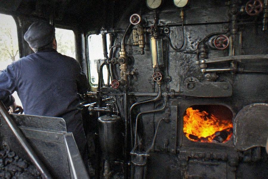 The front of a vintage locomotive with a red and black paint scheme