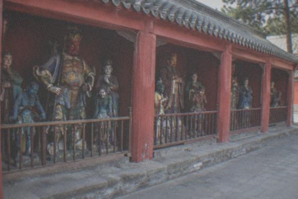 Courtyard of a Chinese temple with stone steles and red-lacquered gates under a grey roof