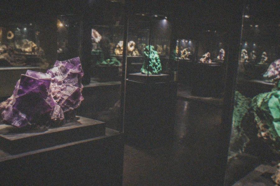 A tall glass case in the Geological Museum of China displaying large mineral crystal specimens lit from below