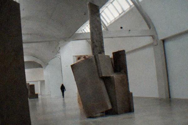 Red brick factory hall with arched windows and a wide empty lane