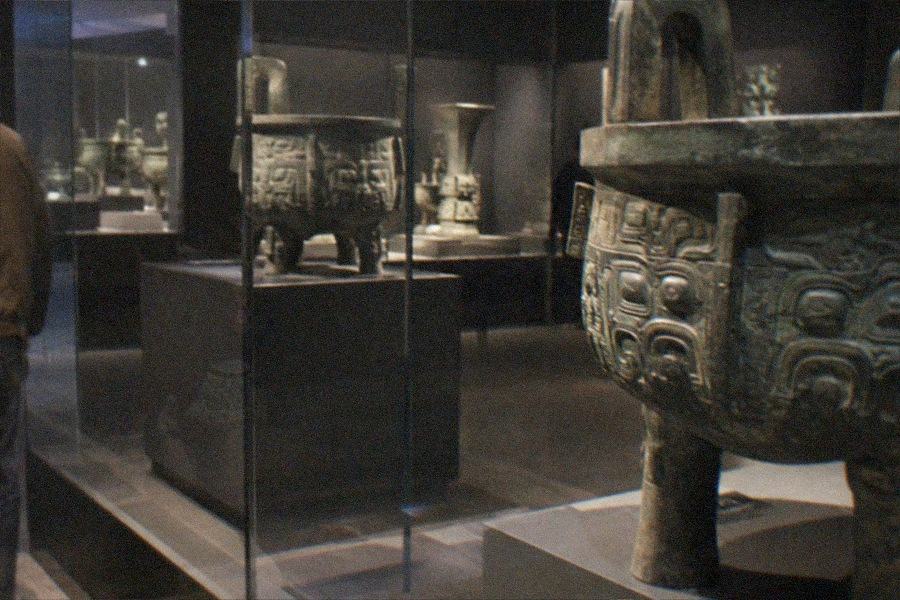 Ancient Chinese bronze ritual vessels displayed in glass cases in the Poly Art Museum galleries