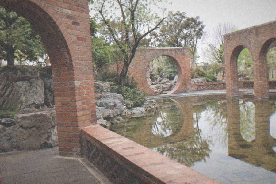 Red Brick Art Museum courtyard with tall red brick walls, a circular opening and visitors walking between galleries
